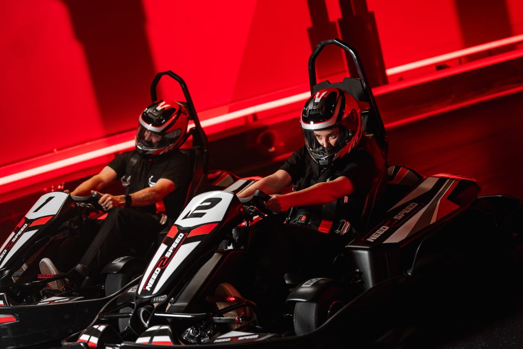 Two people racing go karts on an indoor karting track