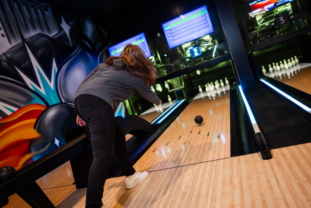 Woman rolling a ball down the lane at a duckpin bowling alley